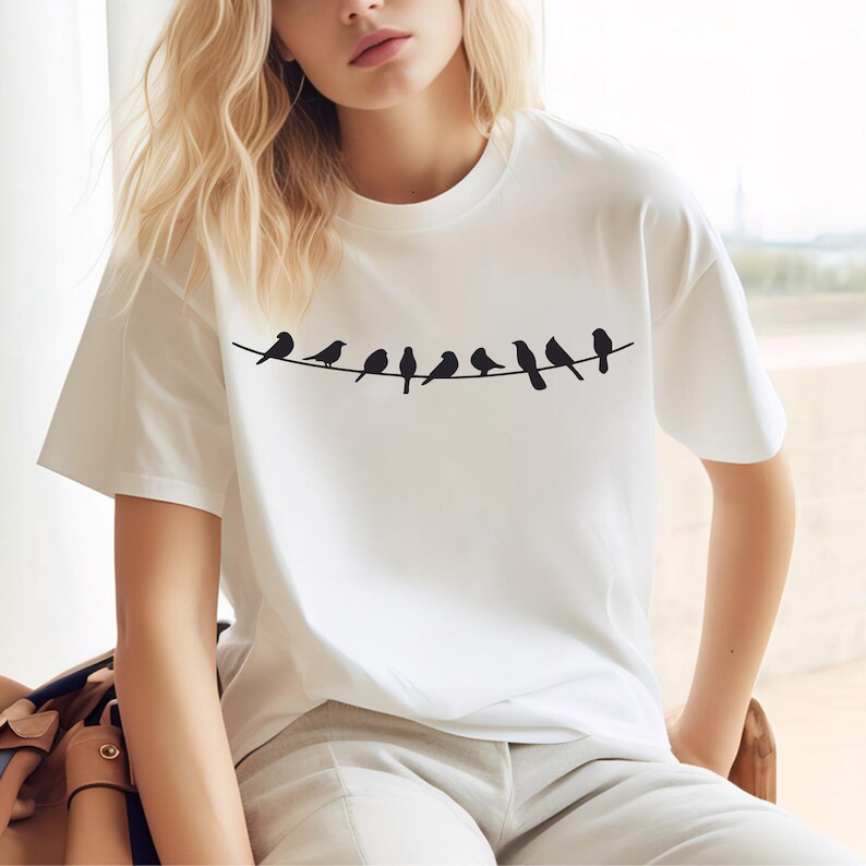 May include: White t-shirt with a black silhouette of birds on a wire graphic print.