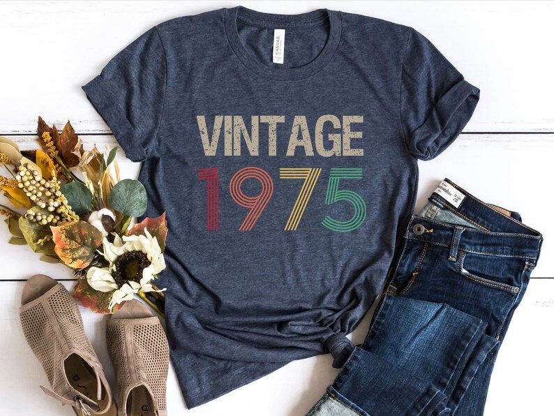 May include: A navy blue t-shirt with a vintage-style graphic that says "Vintage 1975" in red, yellow, and green.