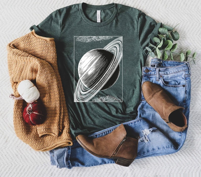 May include: A dark green t-shirt with a vintage illustration of Saturn with its rings. The illustration is in black and white and is centered on the shirt.