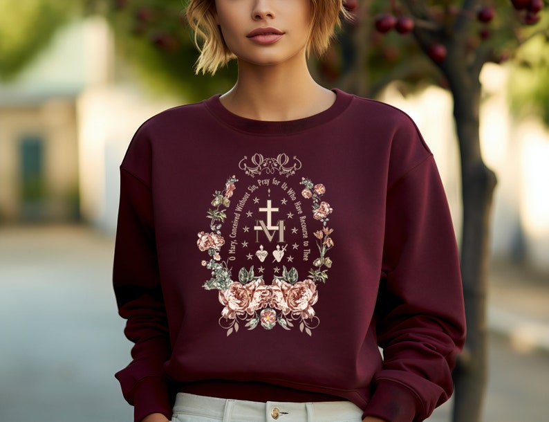 May include: Burgundy sweatshirt with a floral design and the text "O Mary, Conceived Without Sin. Pray for Us Who Have Recourse to Thee" in a gold font.