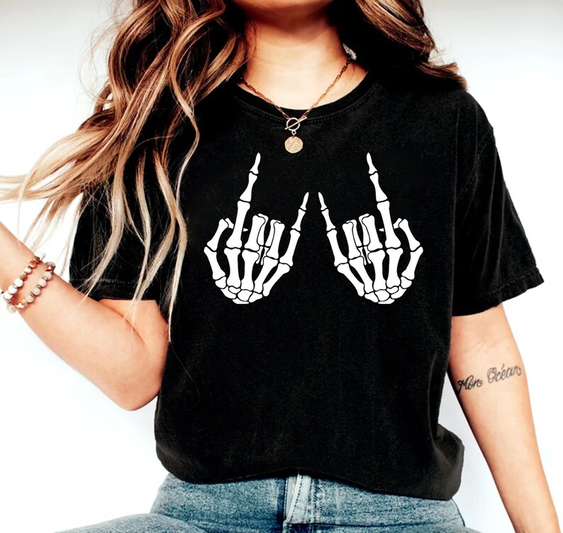 May include: Black t-shirt with a white graphic of two skeleton hands giving the middle finger.