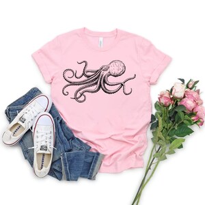 May include: A pink t-shirt with a black and white illustration of an octopus on the front.