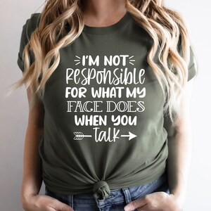 K&ouml;nnte beinhalten: Ein gr&uuml;nes T-Shirt mit wei&szlig;em Text, der "Ich bin nicht verantwortlich f&uuml;r das, was mein Gesicht tut, wenn du sprichst" lautet, mit einem wei&szlig;en Pfeil, der nach rechts zeigt.