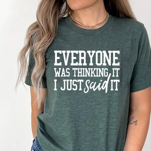 Pu&ograve; includere: Una maglietta verde scuro con il testo "Everyone was thinking it I just said it" in bianco.