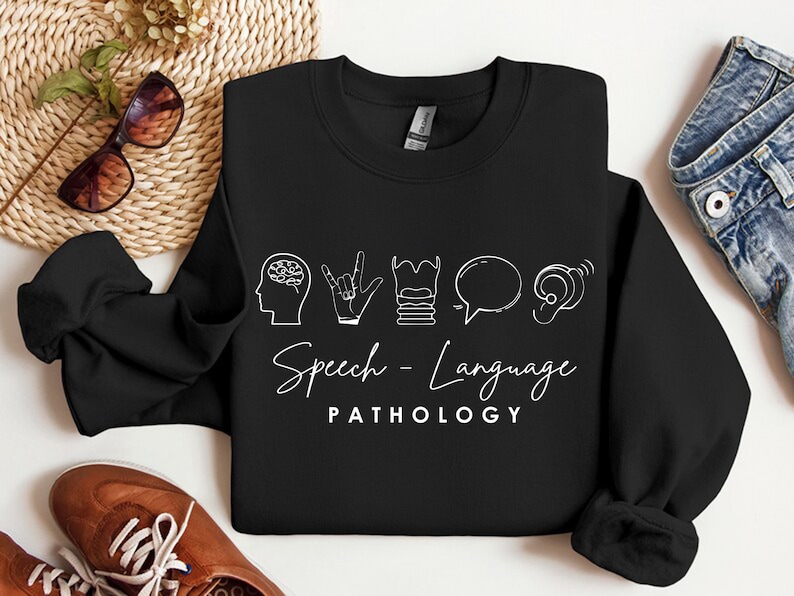 May include: Black sweatshirt with white text and icons that say "Speech-Language Pathology". The icons include a brain, a hand making the sign for "I love you", a stack of books, a speech bubble, and an ear.