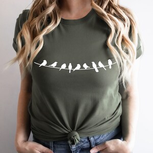 May include: A green t-shirt with a white silhouette of a line of birds on a wire.