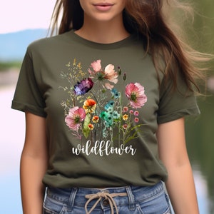 May include: A green t-shirt featuring a watercolour floral design and the word "wildflower" printed in white on the front.