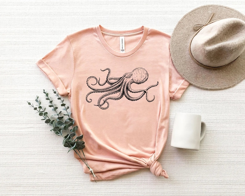 May include: A light pink t-shirt with a black and white illustration of an octopus on the front.