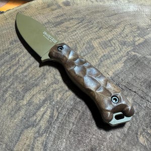 May include: A brown and green fixed blade knife with a wood handle. The blade has the text "BK-14 BAR" and "GEAR MF" on it.