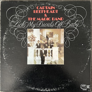 May include: Black and white vinyl record cover with a photo of a band in a grand hallway. The album title is "Captain Beefheart & The Magic Band Lick My Decals Off, Baby".