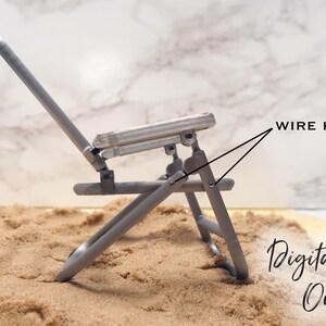 May include: A silver metal folding chair with wire hinges. The chair is sitting on a bed of sand. Digital File Only.