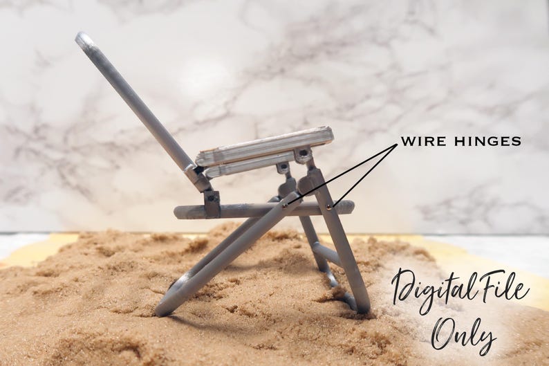 May include: A silver metal folding chair with wire hinges. The chair is sitting on a bed of sand. Digital File Only.