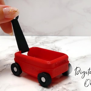 Op de afbeelding: Een rode speelgoedwagen met een zwarte handgreep. De wagen heeft vier wielen en is gemaakt van plastic.