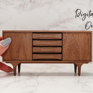 May include: A miniature wooden sideboard with four drawers and two doors. The sideboard is a dark brown color and has a wood grain pattern. It has four legs and is sitting on a white marble surface.