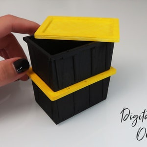 May include: Three black plastic storage containers with yellow lids. The top lid is open. The containers are stacked on top of each other.