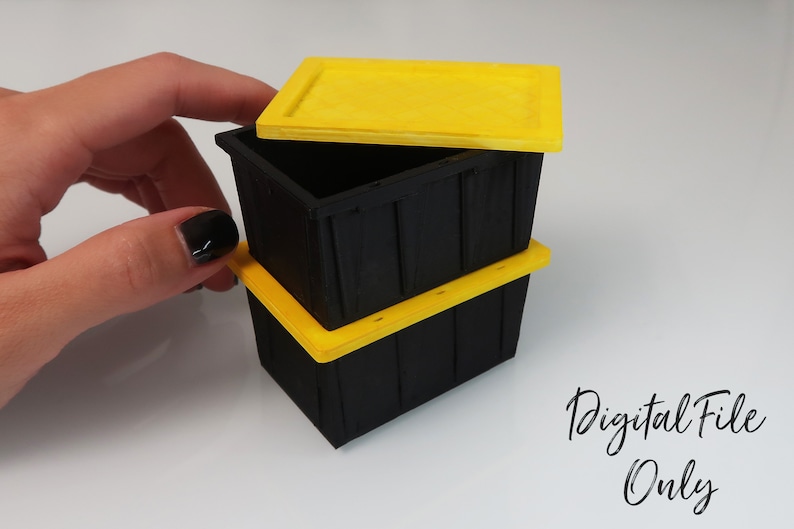 May include: Three black plastic storage containers with yellow lids. The top lid is open. The containers are stacked on top of each other.