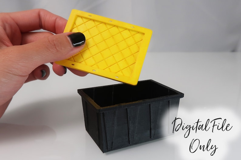 May include: A black plastic storage bin with a yellow lid. The lid has a diamond pattern and is being lifted off the bin. The text "Digital File Only" is visible in the lower right corner of the image.
