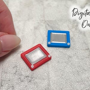 May include: Miniature red and blue toys with a silver screen, resembling a classic drawing toy. The toys are rectangular with white knobs on the sides. The text "Digital File Only" is in the background.