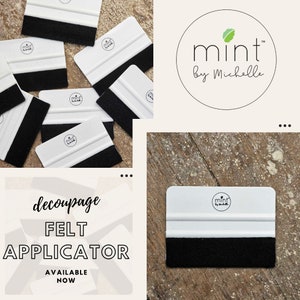Puede incluir: Un conjunto de aplicadores de fieltro blanco con fieltro negro en la parte inferior. Los aplicadores est&aacute;n etiquetados con "mint by Michelle".
