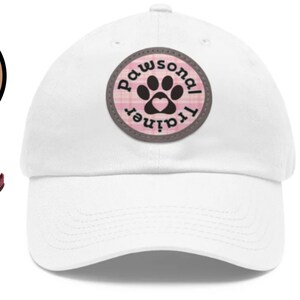 May include: White baseball cap with a pink and white paw print patch that says "Pawsonal Trainer". A brown speech bubble says "Get a Matching Bandana!" and a brown and white dog wearing a pink and white bandana with the same paw print patch is looking up.