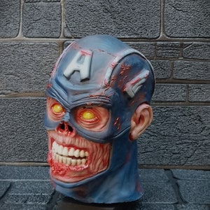 May include: A blue and red zombie Captain America mask with a cracked and weathered appearance. The mask has a large, toothy grin and yellow eyes.