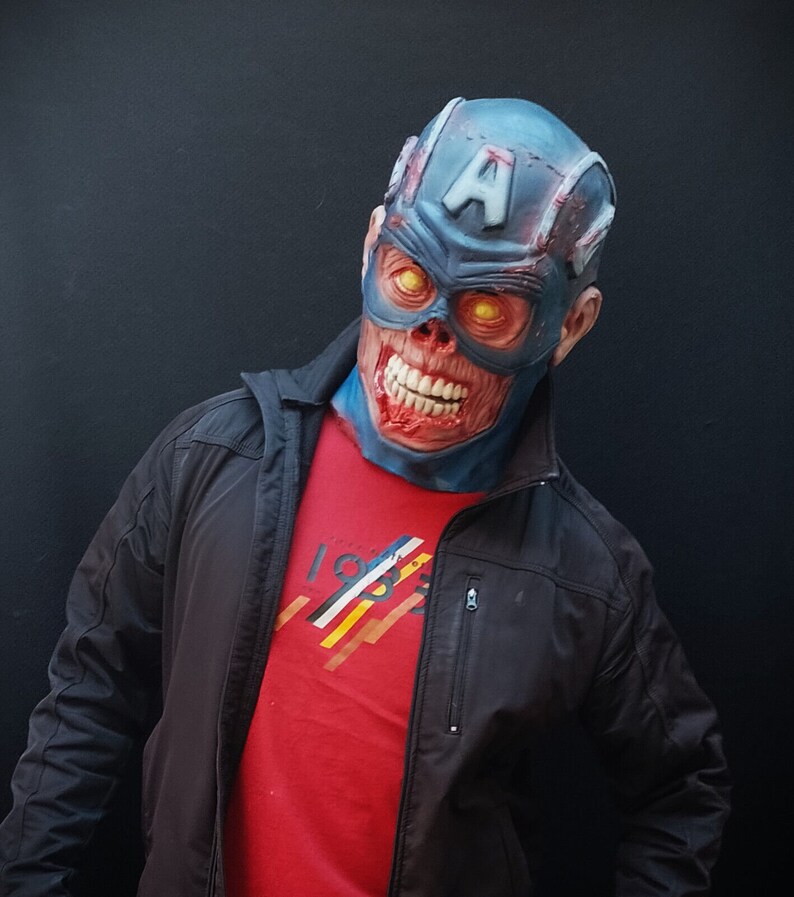 May include: A person wearing a blue and red zombie Captain America mask with a black jacket and red shirt. The shirt has a graphic design with the number 1983.