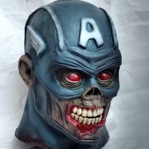 May include: A blue and gray zombie Captain America mask with red eyes and a bloody mouth. The mask has a white "A" on the forehead.