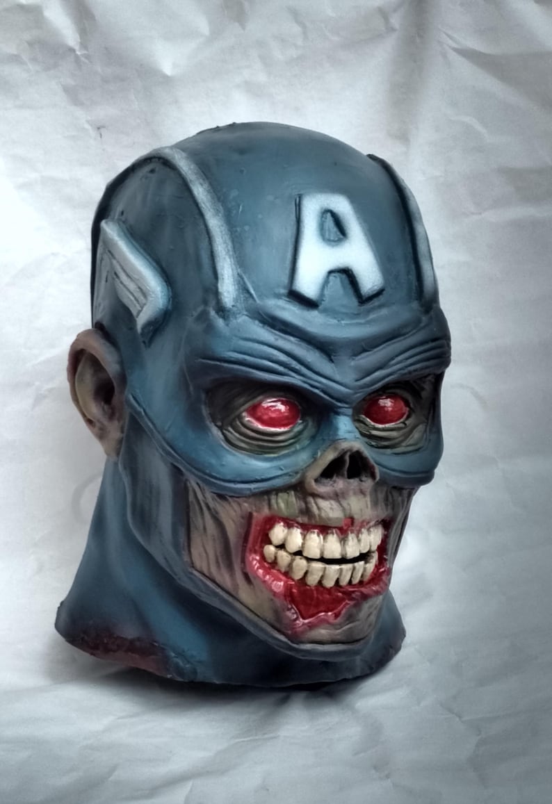 May include: A blue and gray zombie Captain America mask with red eyes and a bloody mouth. The mask has a white "A" on the forehead.