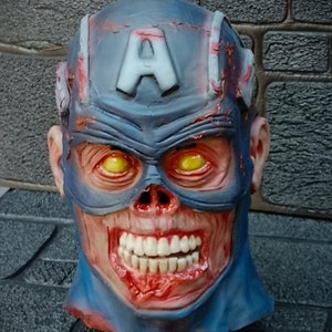 May include: A blue and red zombie Captain America mask with a cracked and bloody appearance. The mask has a white 'A' on the forehead and yellow eyes.