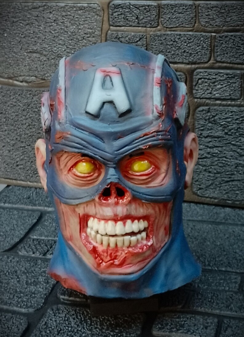 May include: A blue and red zombie Captain America mask with a cracked and bloody appearance. The mask has a white 'A' on the forehead and yellow eyes.
