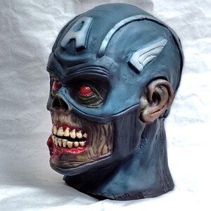 May include: A blue and white zombie Captain America mask with red eyes and a torn mouth. The mask is made of plastic and has a realistic look.