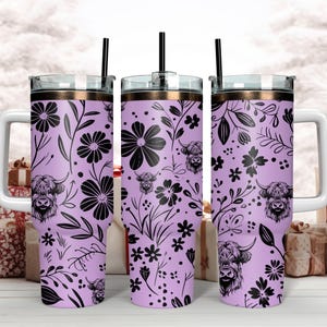 May include: Three stainless steel tumblers with a lavender background and black floral and highland cow designs. The tumblers have lids and straws.