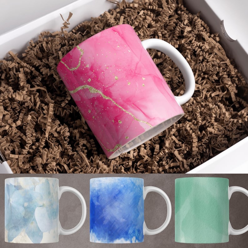 May include: Three ceramic mugs with different watercolor designs. The first mug has a light blue watercolor design, the second mug has a blue watercolor design, and the third mug has a green watercolor design.