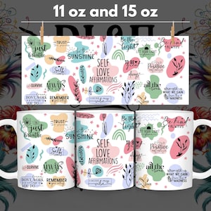 May include: Two white ceramic mugs with a colorful design featuring inspirational quotes and phrases. The mugs are available in 11 oz and 15 oz sizes.