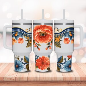 May include: Three white travel mugs with floral designs. The mugs have a handle and a straw. The floral designs feature orange, blue, and green colors.