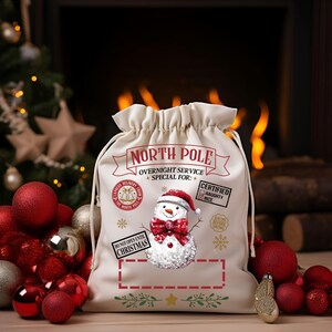Puede incluir: Un saco de Santa de lona blanca con un dise&ntilde;o de mu&ntilde;eco de nieve y el texto "NORTH POLE OVERNIGHT SERVICE SPECIAL FOR: CERTIFIED NAUGHTY NICE DO NOT OPEN UNTIL CHRISTMAS".