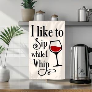 Puede incluir: Toalla de cocina blanca con texto negro que dice "Me gusta sorber mientras azote" y un gr&aacute;fico de copa de vino tinto.