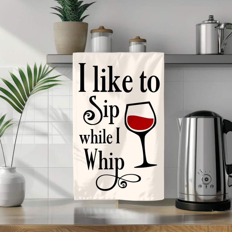 Puede incluir: Toalla de cocina blanca con texto negro que dice "Me gusta sorber mientras azote" y un gr&aacute;fico de copa de vino tinto.