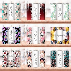 Puede incluir: Conjunto de 10 vasos de acero inoxidable personalizados con diferentes dise&ntilde;os. Los vasos tienen un fondo blanco con un dise&ntilde;o colorido en un lado y el nombre "Elizabeth" en el otro.