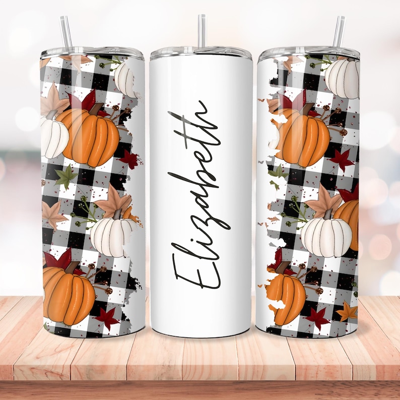 Puede incluir: Tres vasos de acero inoxidable con un dise&ntilde;o de tem&aacute;tica oto&ntilde;al. Los vasos presentan un patr&oacute;n de cuadros de b&uacute;falo blanco y negro con calabazas naranjas, calabazas blancas y hojas de oto&ntilde;o. El vaso del medio tiene el nombre "Elizabeth" escrito en cursiva negra.