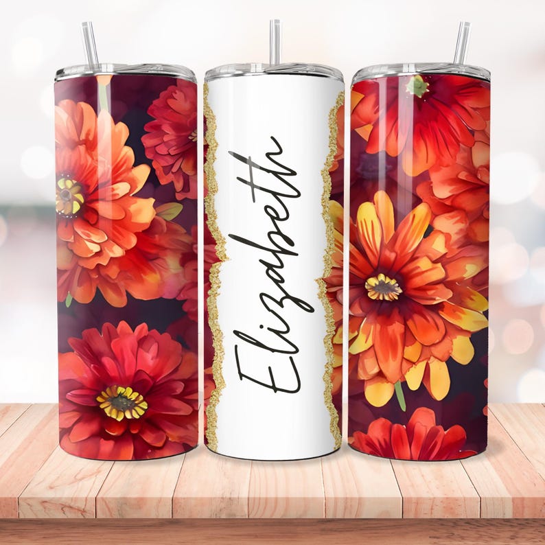 Puede incluir: Tres vasos de acero inoxidable con un dise&ntilde;o floral. El vaso del centro es blanco con detalles de purpurina dorada y el nombre "Elizabeth" escrito en cursiva negra. Los vasos a cada lado presentan un patr&oacute;n floral rojo y naranja.