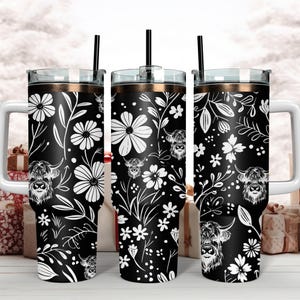 May include: Three black and white stainless steel tumblers with a floral and highland cow design. The tumblers have a gold lid and a straw.