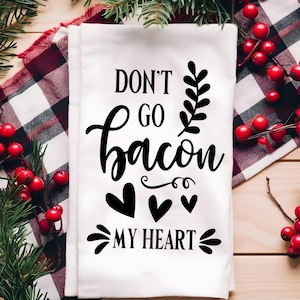 Puede incluir: Toalla de cocina blanca con texto negro que dice "Don't go bacon my heart". El texto est&aacute; en una fuente cursiva y est&aacute; rodeado de tres corazones negros.