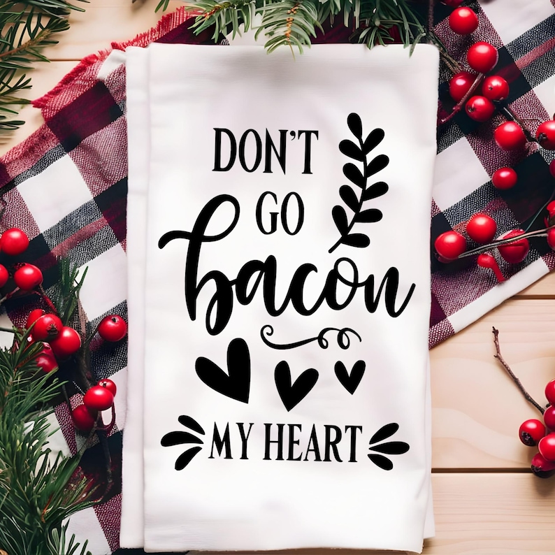 Puede incluir: Toalla de cocina blanca con texto negro que dice "Don't go bacon my heart". El texto est&aacute; en una fuente cursiva y est&aacute; rodeado de tres corazones negros.