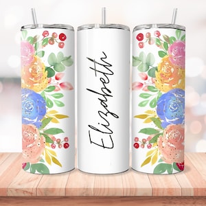 Puede incluir: Tres vasos de acero inoxidable con fondo blanco y un dise&ntilde;o floral en tonos rosa, amarillo, azul y verde. El vaso del medio tiene el nombre "Elizabeth" escrito en cursiva negra.