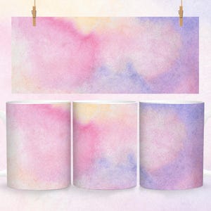 May include: Three white ceramic mugs with a watercolor design. The design features shades of pink, purple, and yellow in a soft, abstract pattern.