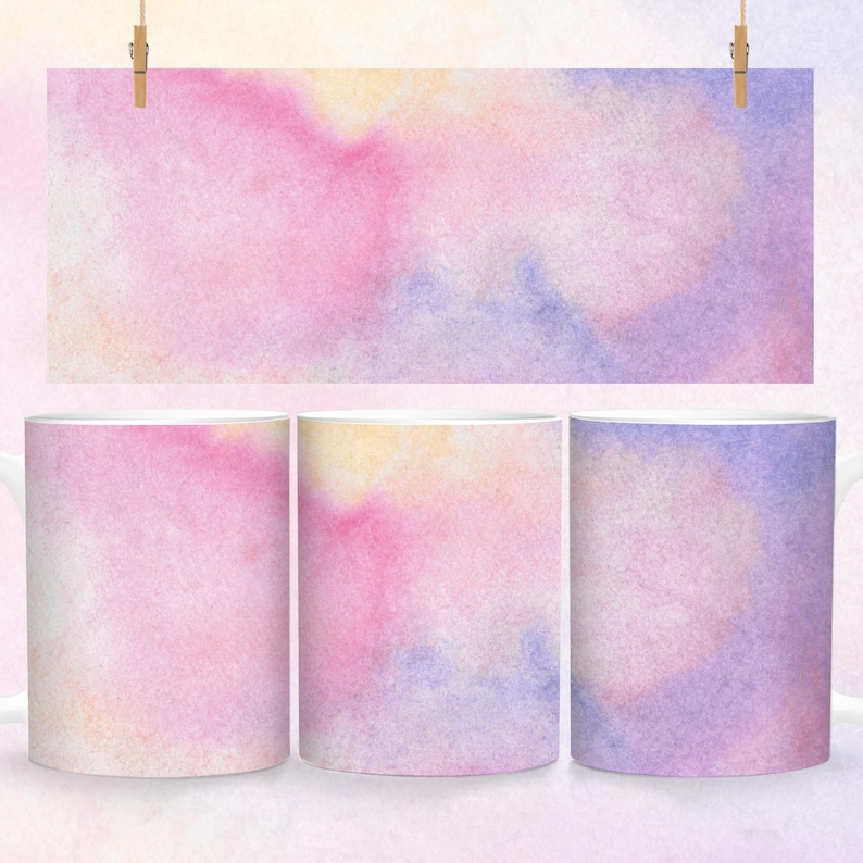 May include: Three white ceramic mugs with a watercolor design. The design features shades of pink, purple, and yellow in a soft, abstract pattern.