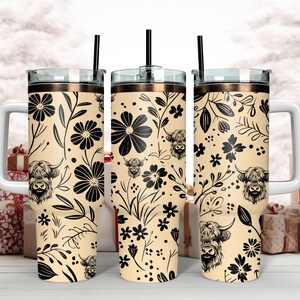 May include: Three stainless steel tumblers with a cream background and black floral pattern. The pattern includes stylized flowers, leaves, and Highland cattle. Each tumbler has a lid and a straw.