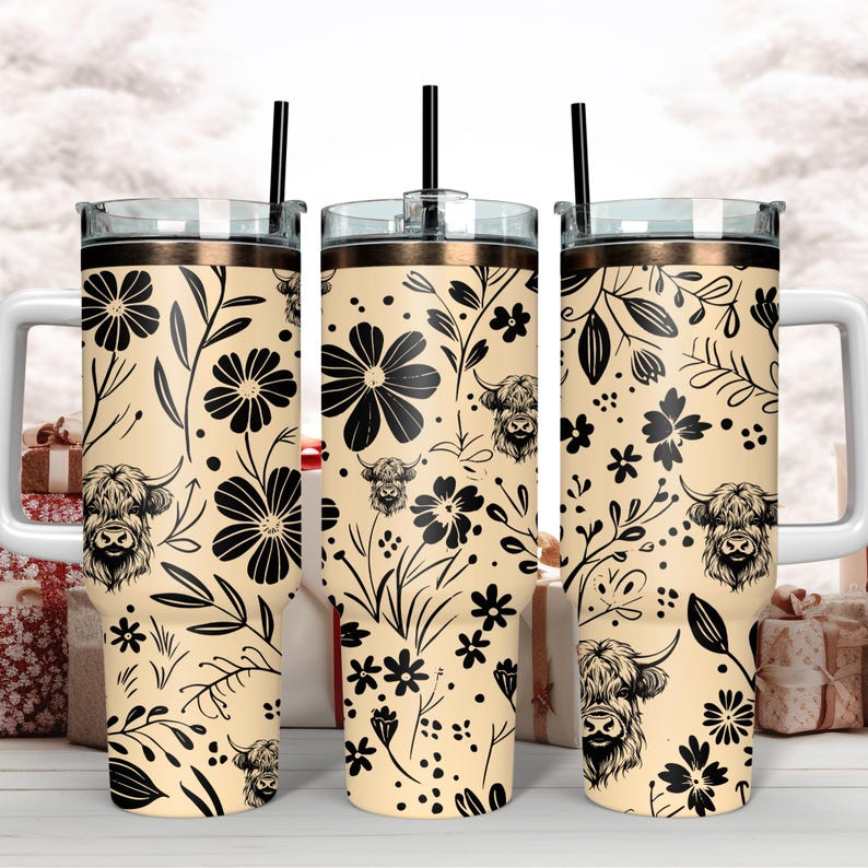 May include: Three stainless steel tumblers with a cream background and black floral pattern. The pattern includes stylized flowers, leaves, and Highland cattle. Each tumbler has a lid and a straw.