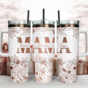 May include: Three white stainless steel tumblers with rose gold accents and floral designs. The tumblers have lids and straws. The tumblers are personalized with the names "Maria", "Brandon", and "Shopia" and the word "MAMA".